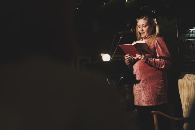 Rosanna Fellman läser ur en bok på en scen.