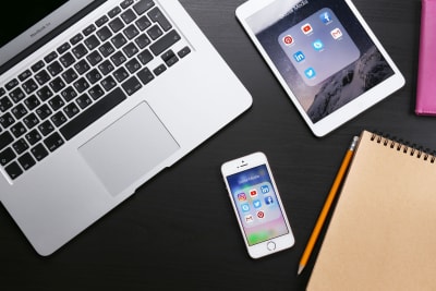 En iPhone, iPad och Macbook på ett bord.