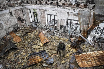 Sotilas seisoo tuhoutuneen koulurakennuksen raunioissa.