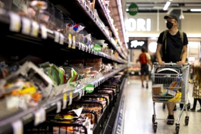 Man med shoppingvagn kollar utbudet i matbutik. 