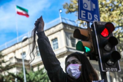 En iransk kvinna håller upp en bit av sitt hår för att protestera mot den islamska regimen. Hon bär ingen slöja på huvudet.