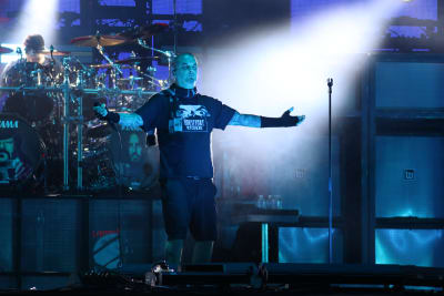 En man står med armarna utåt på en scen i blått ljus.