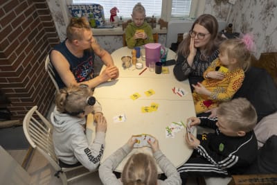 Familjen Flygar spelar kort vid matbordet. Ville, Yvonne. Viggo, Milian, Tristan, Liam och Lilly. 