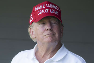 Donald Trump i vit golfskjorta och röd Make America Great Again-keps.