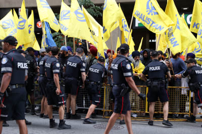 Demonstranter med gula flaggor bakom ett staket som vaktas av konstaplar.