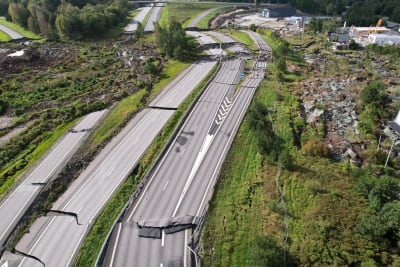 En luftbild av ett avsnitt motorväg med omfattande skador: hela vägen har förskjutits av rasmassor.