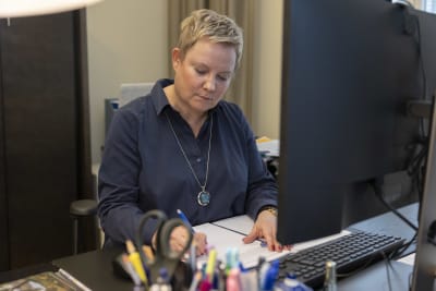 Riksförlikningsman Anu Sajavaara sitter bakom sitt arbetsbord. 