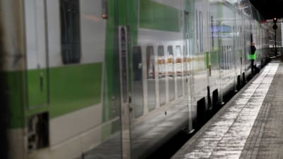 En konduktör syns vid dörren till ett tåg vid Helsingfors centralstation.