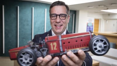 Autoalan Keskusliiton toimitusjohtaja Tero Lausala esittelee pienoismalliautoa.