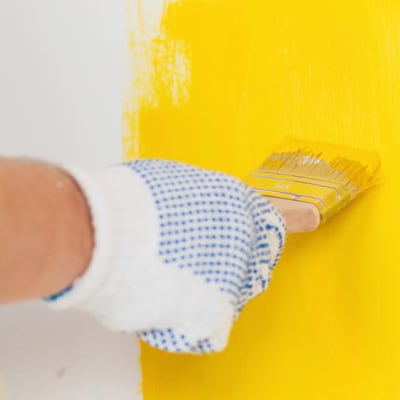 Man som målar gul färg på en vägg.