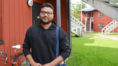 ung man framför faluröda hus