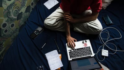 En ung studerande sitter i sängen och studerar.