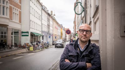Peter Ernstved Rasmussen lutar mot en vägg i stadsmiljö.