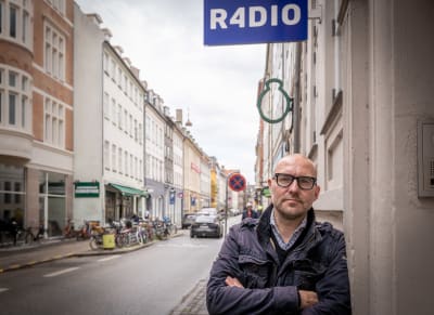 Peter Ernstved Rasmussen lutar mot en vägg i stadsmiljö.