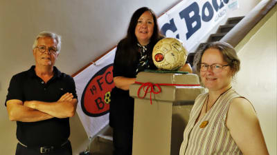 Torbjörn Kevin, Lisa Roberts och Satu Zwerver i en trappa bredvid en gammal fotboll på utställning. 