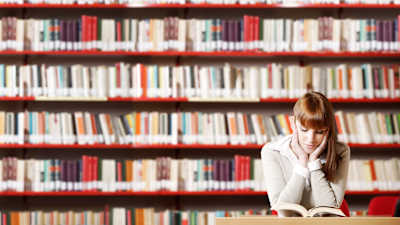 Tyttö lukee kirjastossa