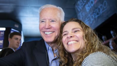 Joe Biden ler stort mot kameran när han poserar med en supporter