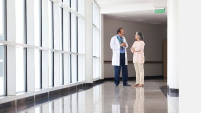 Läkare och patient diskuterar i en sjukhuskorridor.