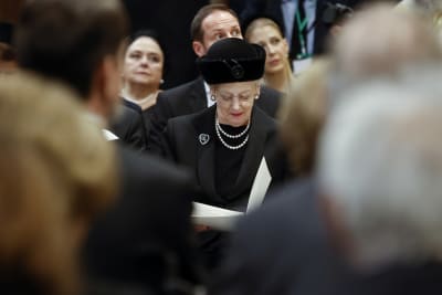 Drottning Margrethe II, klädd i svart, tittar ner i ett programhäfte.