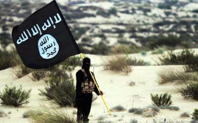 En maskerad man står och håller i IS-flagga.