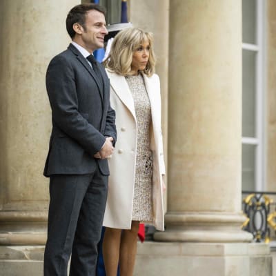 Emmanuel och Brigitte Macron står bredvid varandra och tittar framåt.