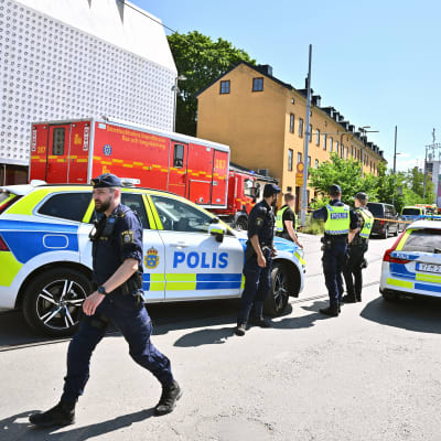 Poliser står vid två polisbilar utanför Gröna Lund.