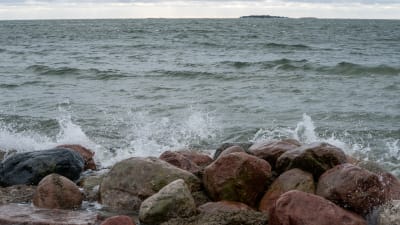 Vågor slår mot en strand med stenar.