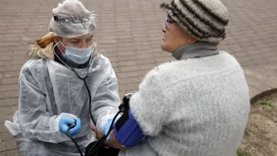 En vårdare mäter blodtrycket på en hemlös kvina i Minsk under en gatumottagning som drivs av frivilliga