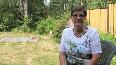 Carita Nurminen sitter utomhus i en stol och tittar mot kameran