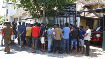 Människor samlas utanför en byggnad efter bombattentat i Sri Lanka