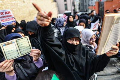 Människor håller upp koranen och demonstrerar.