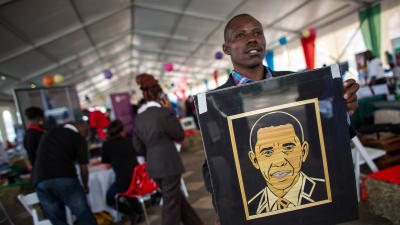 EN kenyansk man håller upp ett porträtt av Barack Obama.
