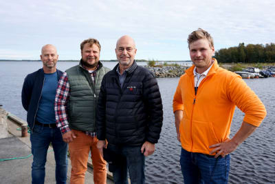 Fyra män står på en brygga.