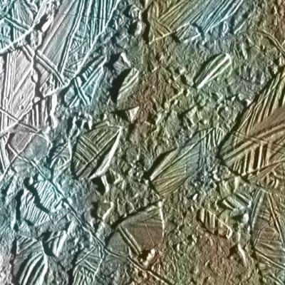 Lähikuva Jupiterin Europa-kuun jääpinnasta.  Kuvassa on halkeamia ja railoja, kraattereita ja laattamaisia painautumia.