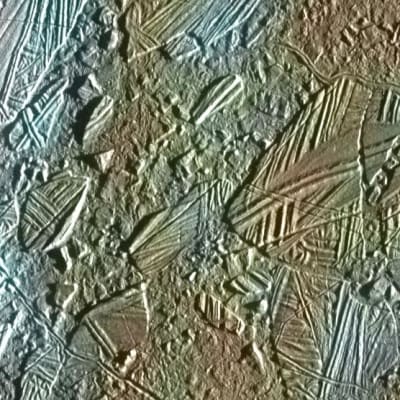 Lähikuva Jupiterin Europa-kuun jääpinnasta.  Kuvassa on halkeamia ja railoja, kraattereita ja laattamaisia painautumia.