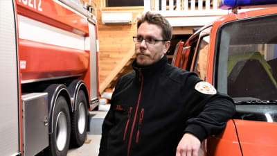 Jyri Huhtala står vid en gammal brandbil. Han är kårchef för Box frivilliga brandkår.