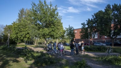Människor och cyklar samlade i Olssonsparken i Lovisa, i bakgrunden syns idrottshallen.