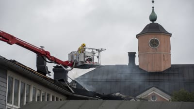 En brandman i en hävare granskar ett brandhärjat tak.