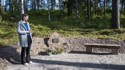 Emilia Mattsson intill en minnessten och en bänk.