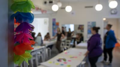 En suddig bild av ett möte i Konstskolan i Borgå, i förgrunden en färgrann blomkrans.