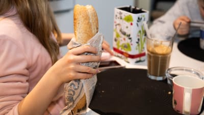 Koululaiset syövät kotona välipalaa.