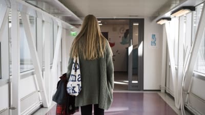En flicka går i en korridor.