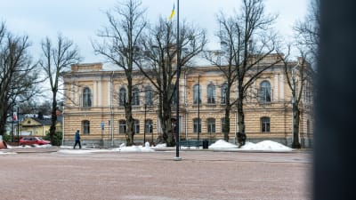 Stadshuset i Borgå på vårvintern, inga löv i träden och Ukrainas flagga i flaggstången.