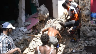 En grupp personer gräver i rasmassorna efter jordbävningen i Haiti. 