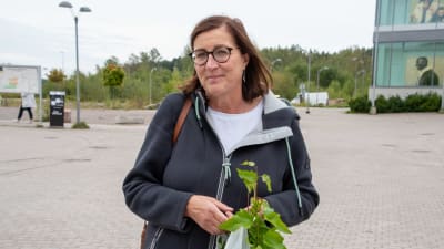 Anne Elenius-Parkkari har en vit plastpåse med björkplantor i. 