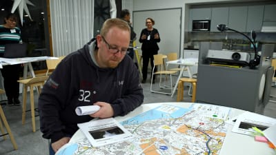 En man sitter vid ett runt bord och studerar en karta.