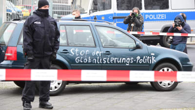 En polis står framför en bil som målats med texten "Stoppa globaliseringspolitiken".