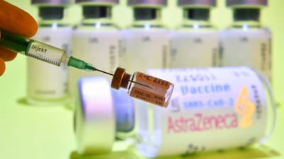 Flera ampuller med vaccin och i förgrunden en injektionsnål som stuckits in i en ampull.