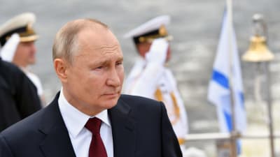 Bild på Rysslands president som står framför marinsoldater.