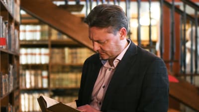 Stefan Hagman läser en bok i Borgå gymnasiums gamla bibliotek.